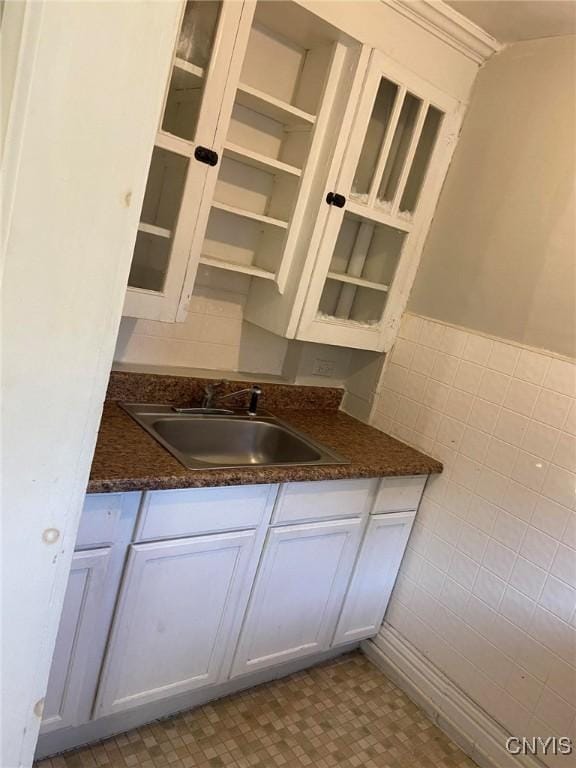 bar featuring sink, white cabinets, and tile walls