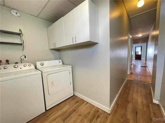 laundry room featuring hardwood / wood-style floors, washer and dryer, and cabinets