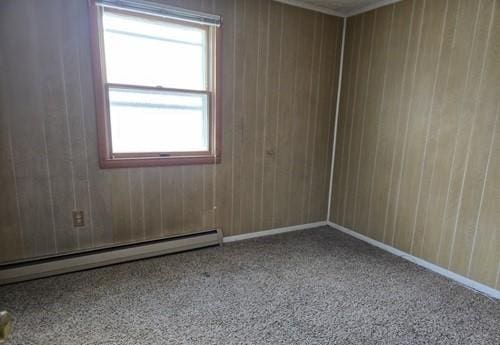 empty room with wood walls and a baseboard heating unit