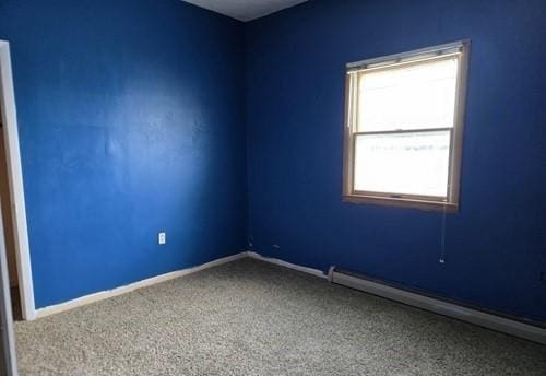 carpeted spare room with plenty of natural light and a baseboard heating unit