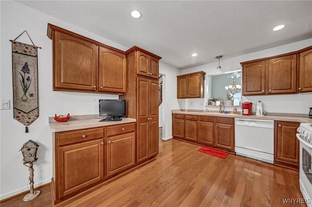 kitchen featuring a textured ceiling, white appliances, sink, an inviting chandelier, and light hardwood / wood-style floors