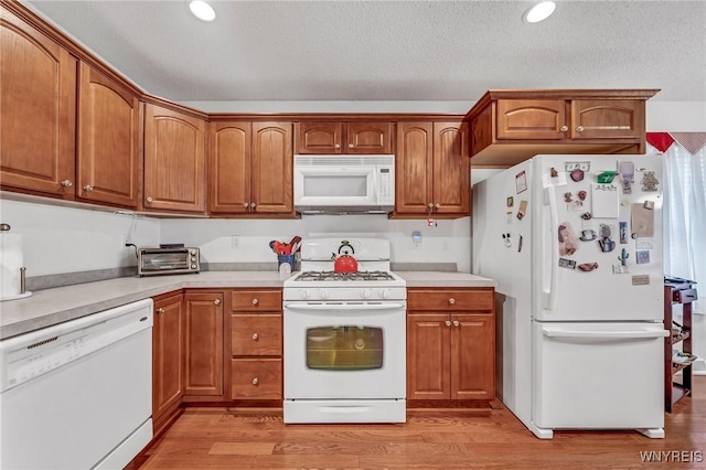 kitchen featuring a textured ceiling, light hardwood / wood-style flooring, and white appliances