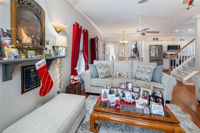 living room with hardwood / wood-style floors, ceiling fan with notable chandelier, and ornamental molding