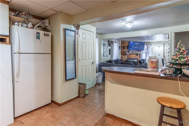 kitchen with kitchen peninsula, light parquet flooring, white fridge, and a breakfast bar area