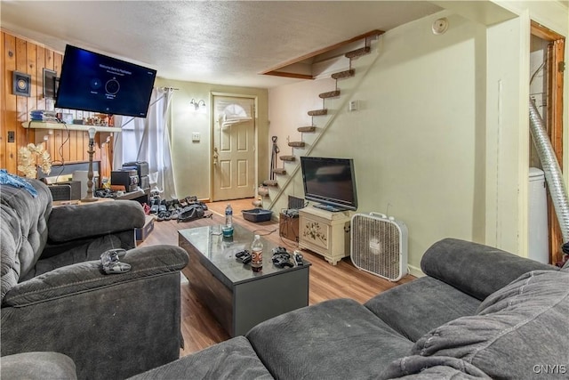 living room with a textured ceiling, hardwood / wood-style flooring, and wood walls