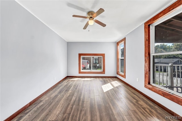 spare room featuring ceiling fan, dark hardwood / wood-style floors, and a wealth of natural light