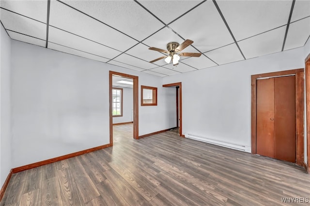 empty room with a paneled ceiling, ceiling fan, a baseboard radiator, and dark hardwood / wood-style floors