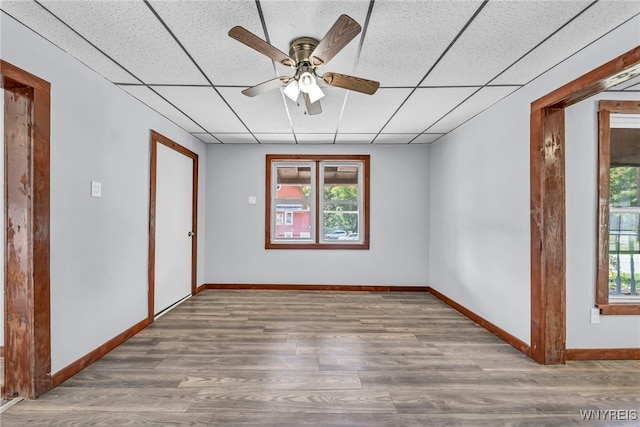 empty room with a paneled ceiling, hardwood / wood-style flooring, and a healthy amount of sunlight