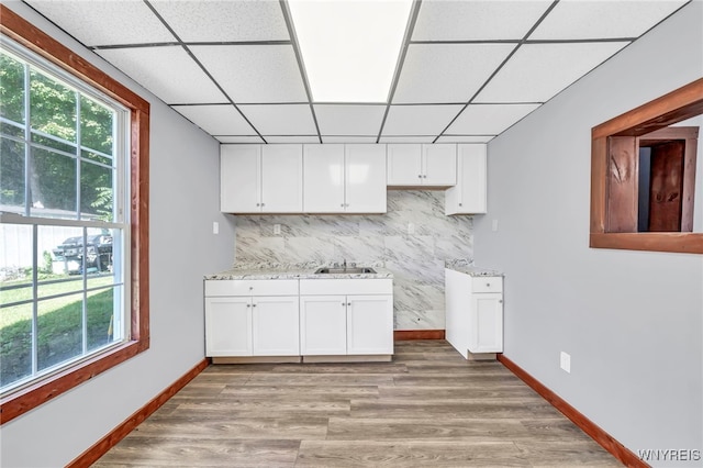 kitchen featuring a paneled ceiling, sink, white cabinets, and light wood-type flooring