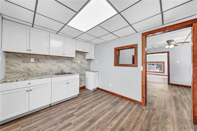 kitchen with tasteful backsplash, ceiling fan, sink, wood-type flooring, and white cabinets