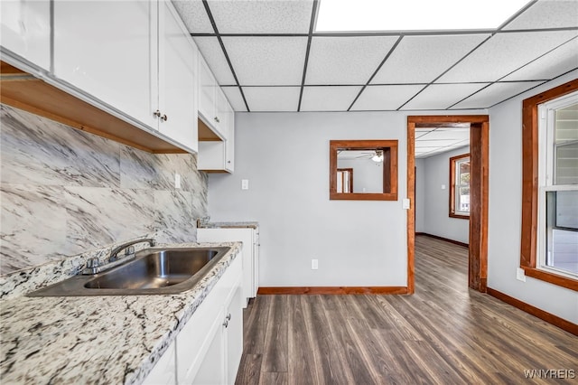 kitchen with white cabinets, decorative backsplash, a drop ceiling, and sink