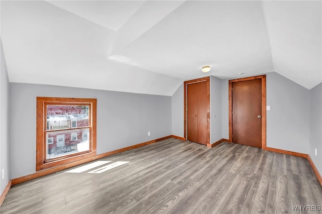 bonus room featuring light wood-type flooring and vaulted ceiling