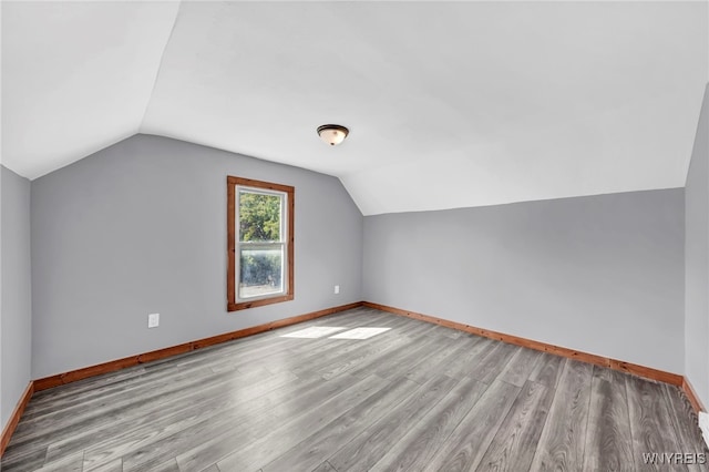 additional living space with lofted ceiling and light hardwood / wood-style flooring