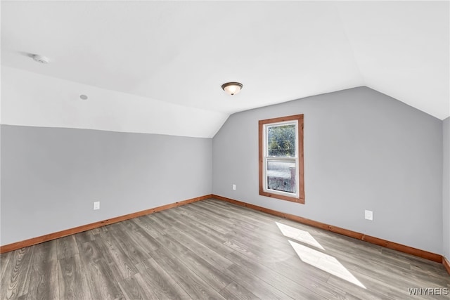 additional living space with light wood-type flooring and lofted ceiling