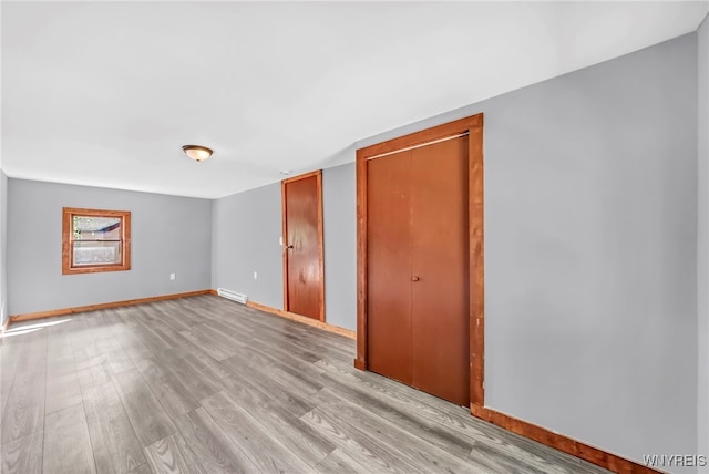 empty room with light hardwood / wood-style floors and baseboard heating