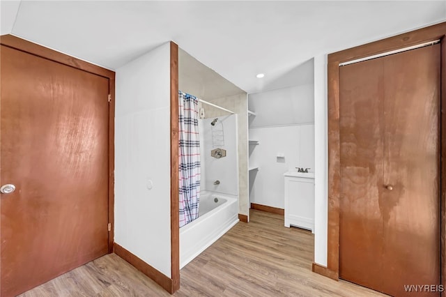 bathroom with hardwood / wood-style floors, vaulted ceiling, shower / bath combo with shower curtain, and sink