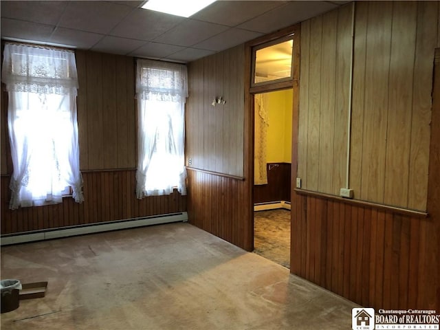 unfurnished room with carpet, wood walls, and baseboard heating