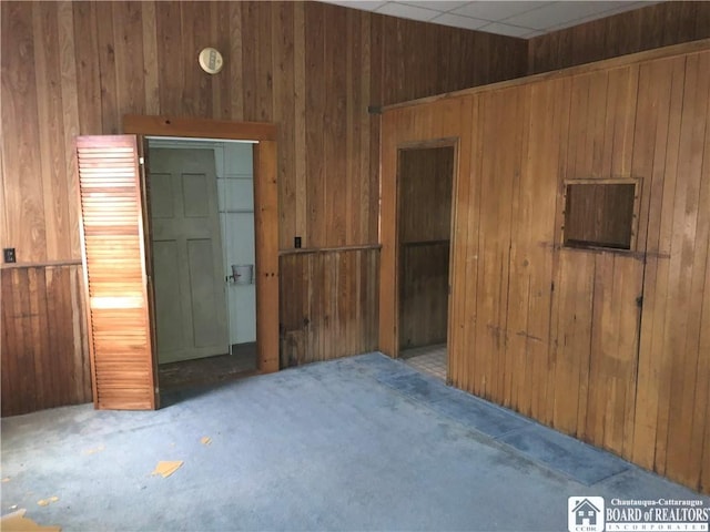 carpeted spare room with wood walls