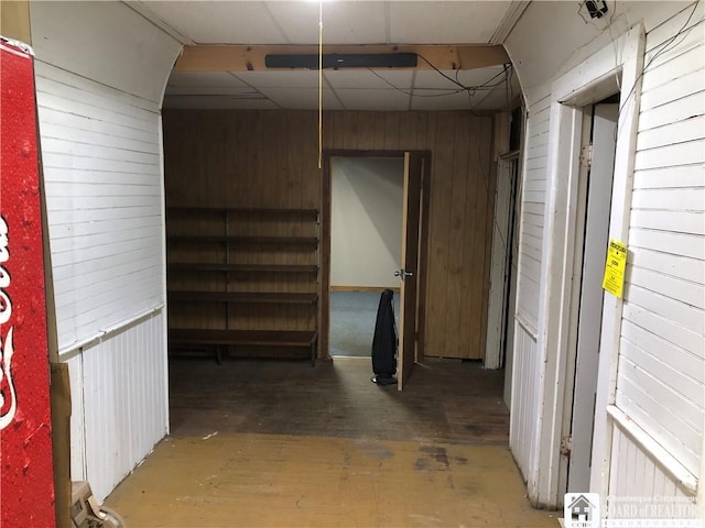 interior space with a paneled ceiling and wood walls