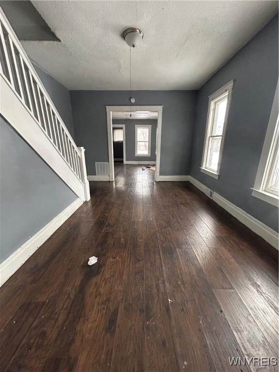 interior space featuring a textured ceiling, plenty of natural light, and dark wood-type flooring