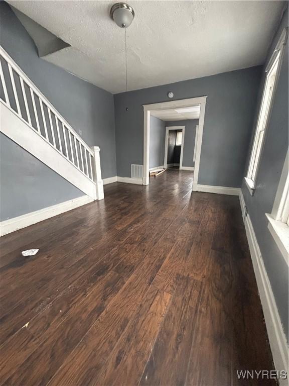 unfurnished living room with a textured ceiling and dark hardwood / wood-style floors