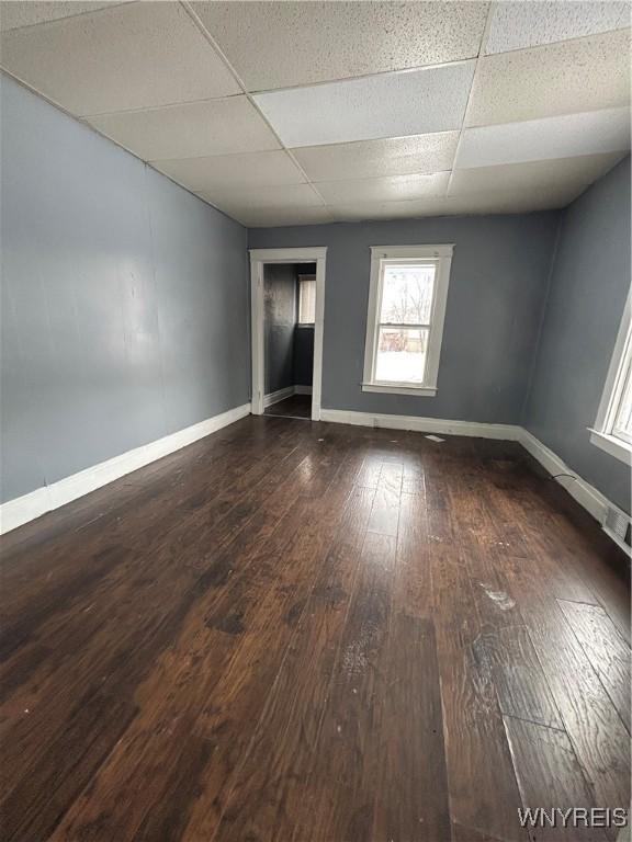 spare room featuring a paneled ceiling and dark wood-type flooring