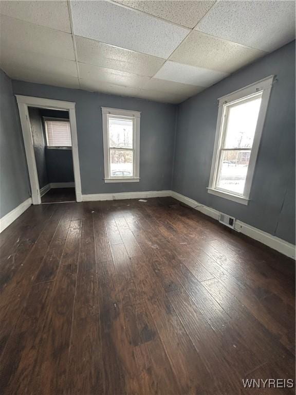 spare room with dark hardwood / wood-style flooring and a paneled ceiling