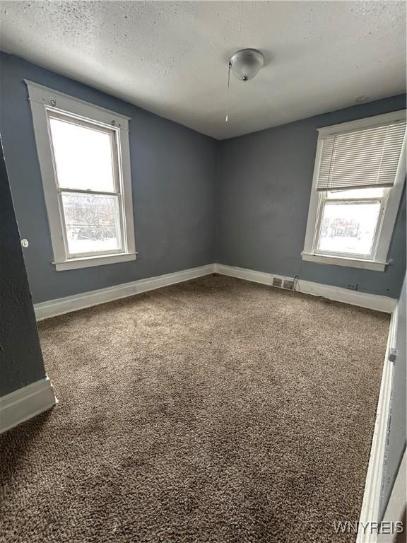 carpeted spare room featuring a textured ceiling