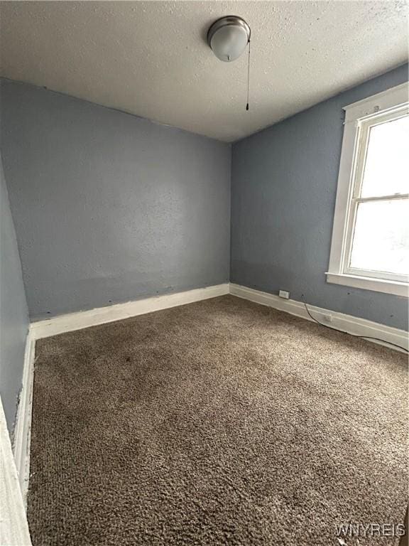 carpeted empty room featuring a textured ceiling