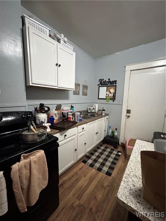 kitchen with electric range, dark hardwood / wood-style floors, white cabinetry, and sink