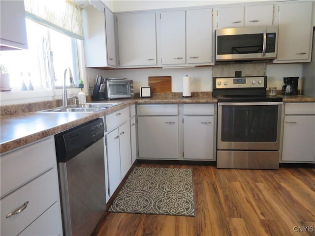 kitchen with dark hardwood / wood-style flooring, white cabinetry, sink, and appliances with stainless steel finishes