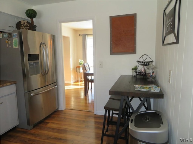 kitchen featuring stainless steel fridge, dark hardwood / wood-style flooring, and white cabinetry