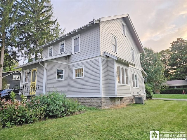 property exterior at dusk featuring a yard and central AC unit