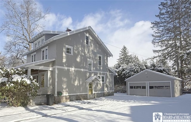 view of snowy exterior featuring an outdoor structure and a garage