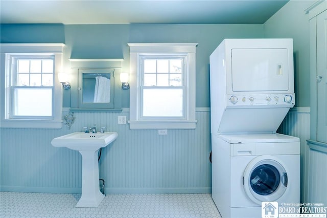 laundry room with wooden walls and stacked washer and clothes dryer