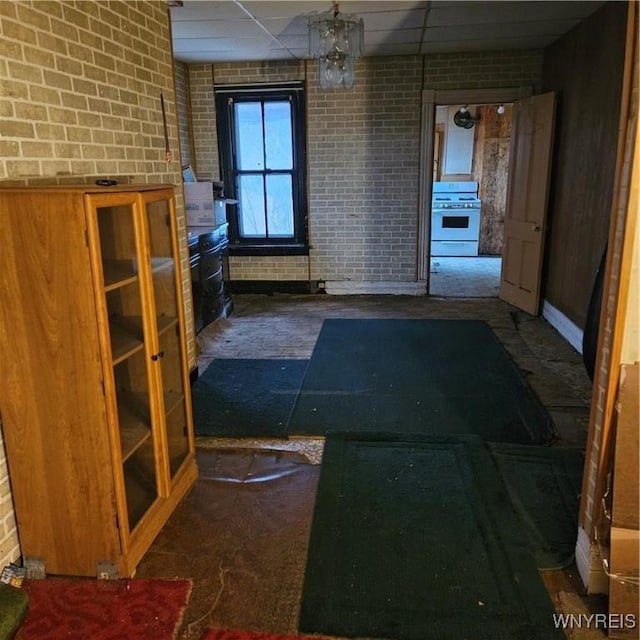 interior space with a drop ceiling and brick wall