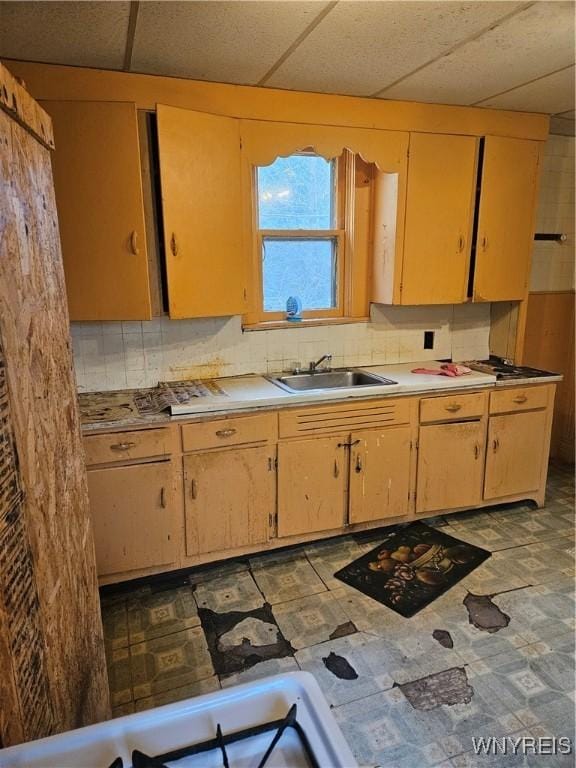 kitchen featuring tasteful backsplash, a drop ceiling, and sink