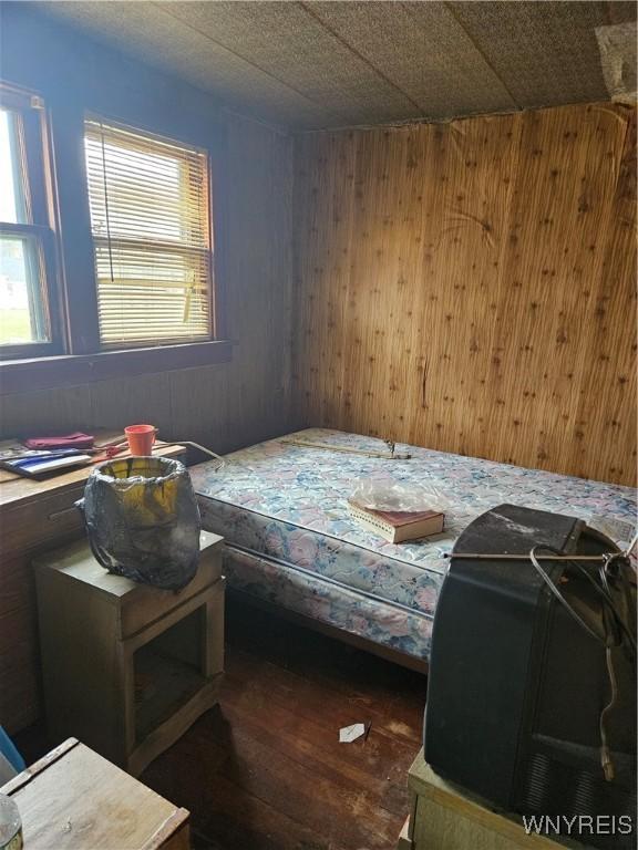 bedroom with dark wood-type flooring and wooden walls