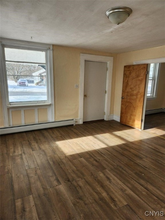 unfurnished room with hardwood / wood-style flooring, a textured ceiling, and a baseboard heating unit