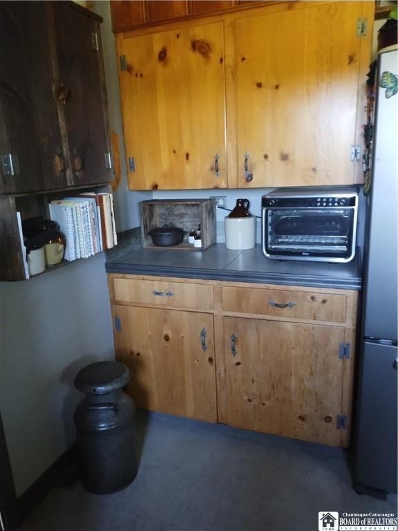 355 New Buffalo Rd, French Creek, NY 14724 - kitchen with freestanding refrigerator, dark countertops, and brown cabinets