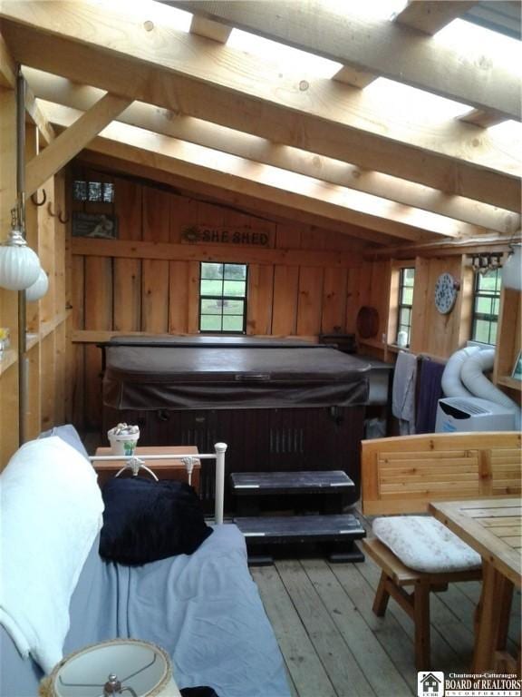 misc room with lofted ceiling, wood-type flooring, and wood walls