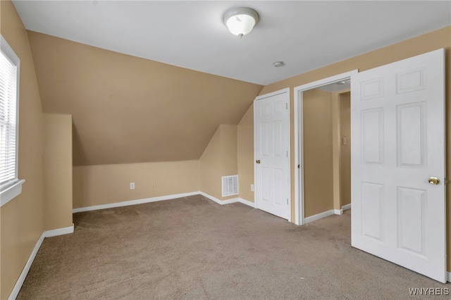 bonus room with light carpet and lofted ceiling