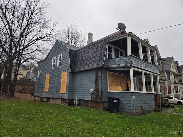 rear view of house featuring a sunroom and a lawn