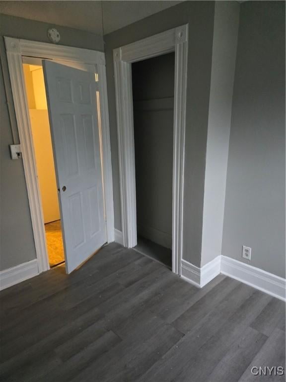 unfurnished bedroom with a closet and dark hardwood / wood-style floors