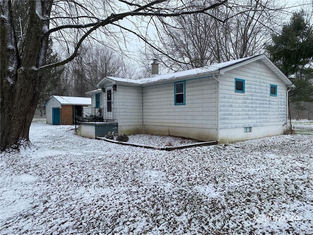 snow covered property with a shed