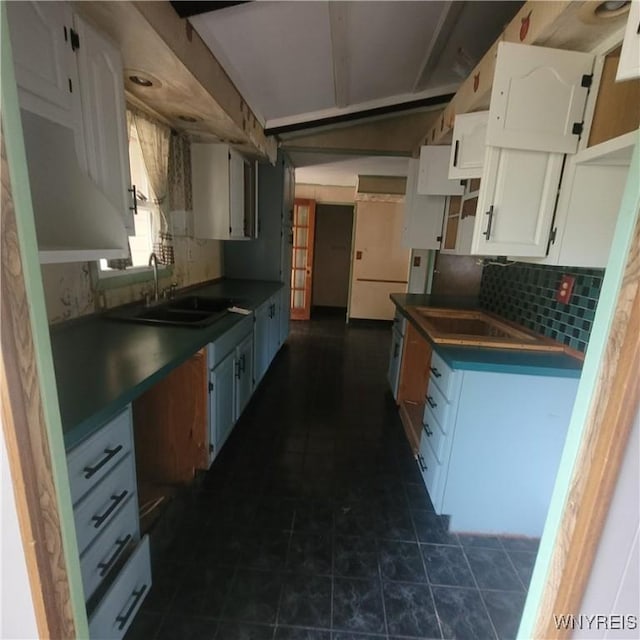 kitchen featuring backsplash, sink, white cabinets, and dark tile patterned floors