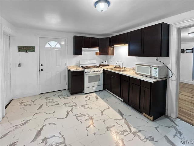 kitchen featuring dark brown cabinetry, sink, and white appliances