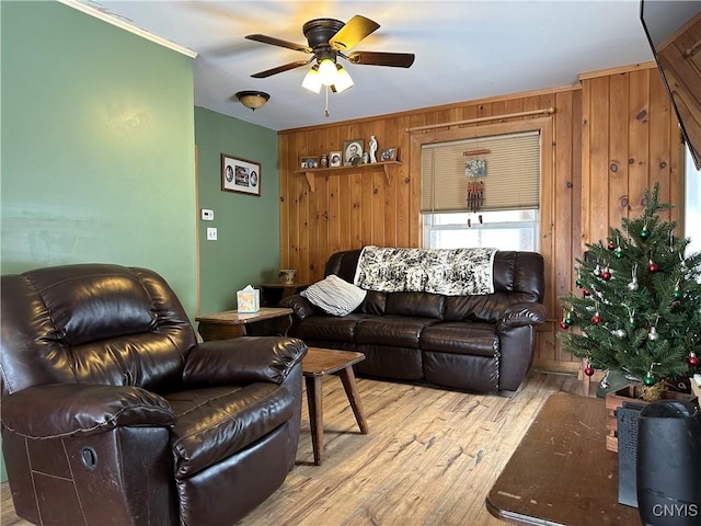 living room with ceiling fan, wood walls, and light hardwood / wood-style flooring