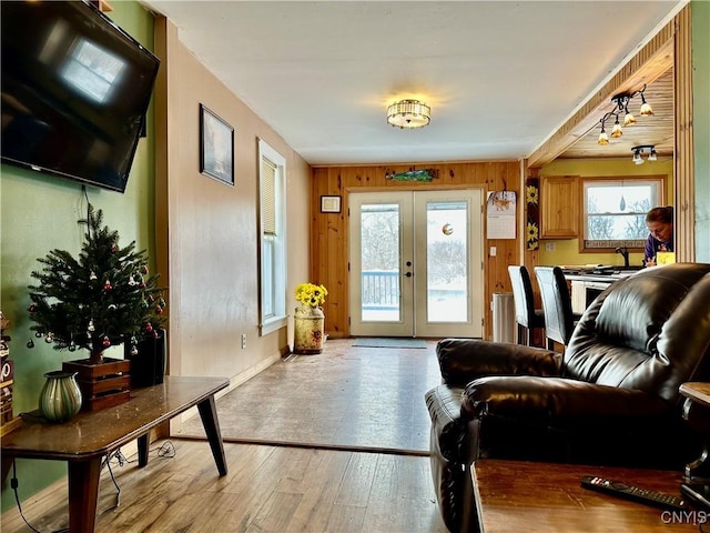 living room featuring wooden walls, french doors, and light wood-type flooring