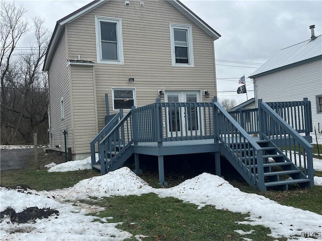 snow covered back of property featuring a lawn and a deck